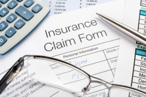 Close up of handwritten Insurance Claim Form with pen and calculator